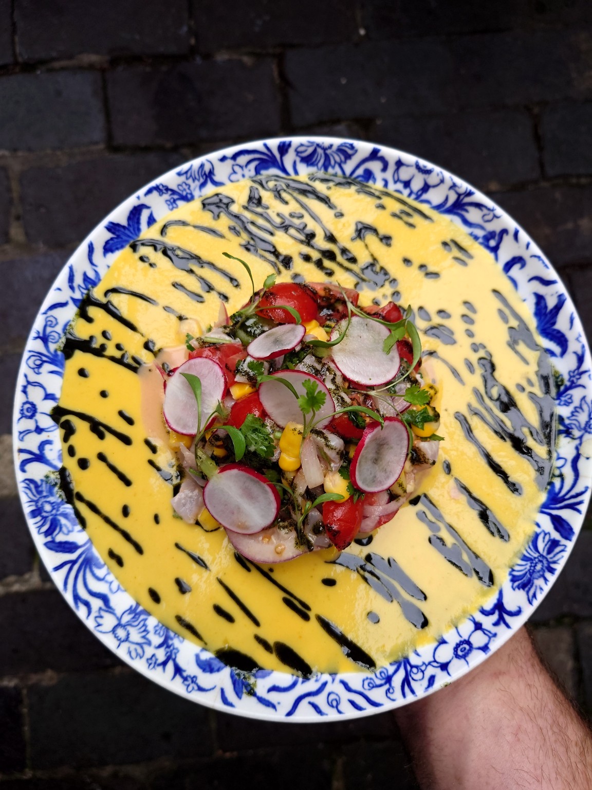 Vegetables, radishes and yellow sauce on a blue-and-white plate